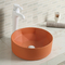 反対のテーブルの上のオレンジ洗面器の上の滑らかな陶磁器の円形の浴室の流し